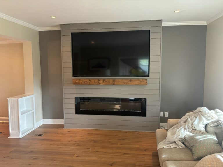 Fireplace accent wall painted grey with a mounted TV and wood mantle