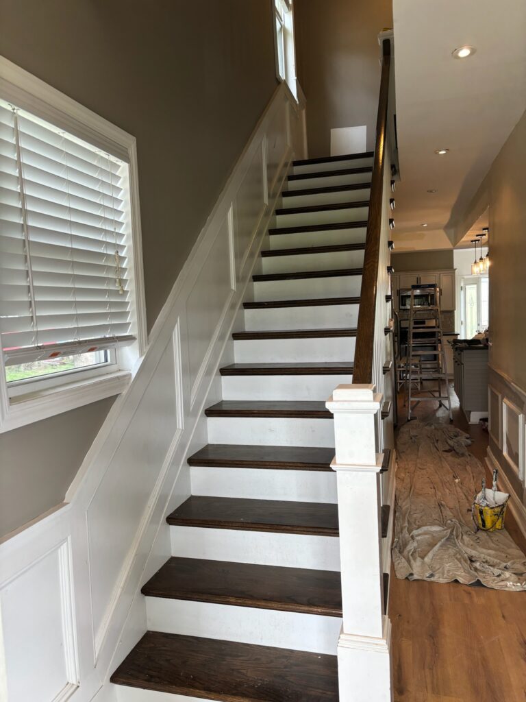 Staircase mid-refinish, with a drop cloth and ladder still in place
