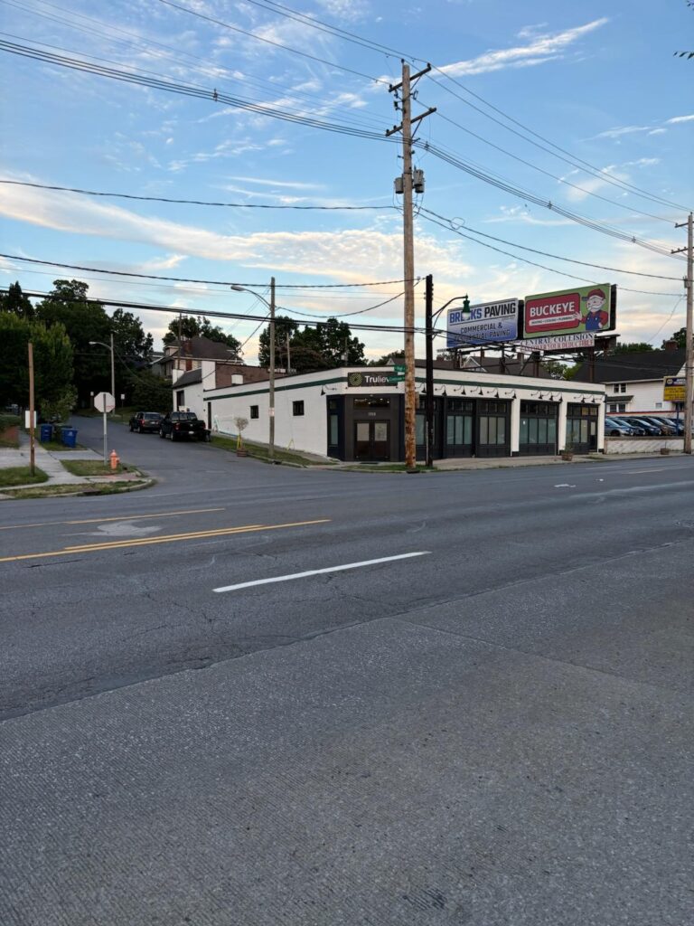 Wide street view of the finished white storefront with black trim at dusk